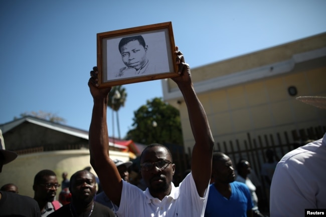 A man shows a portrait of missing local, freelance photojournalist Vladjimir Legagneur, during a march to demand information about his whereabouts, in Port-au-Prince, Haiti, March 28, 2018.