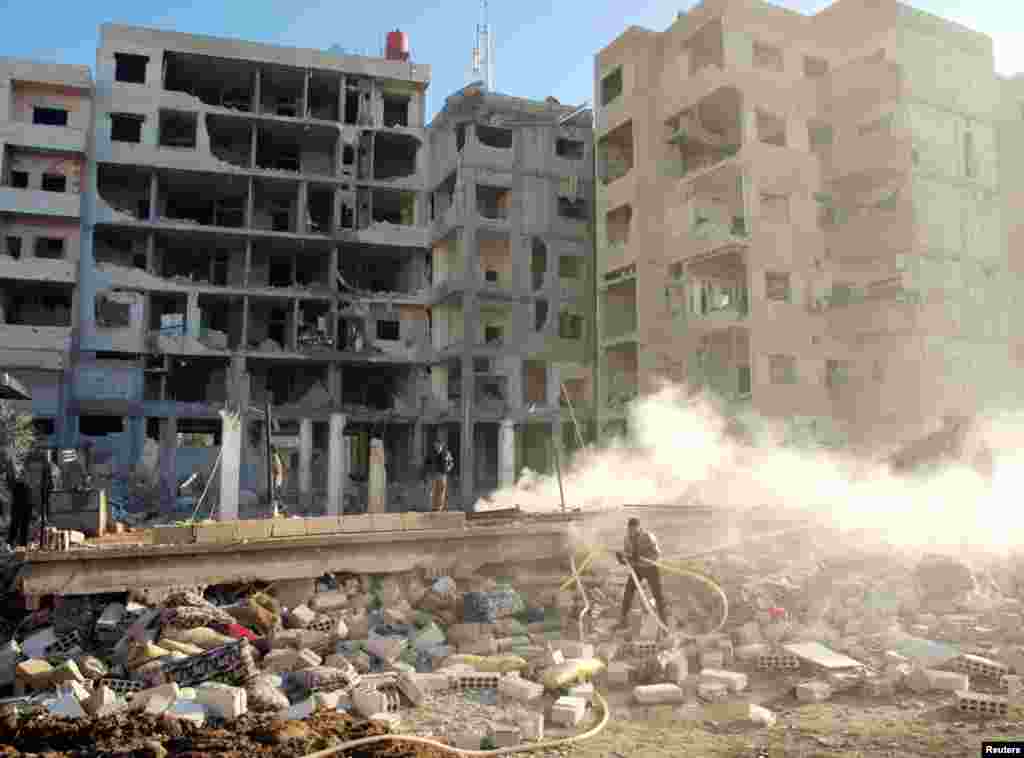 Residents stand near buildings damaged by missiles fired by a Syrian Air Force fighter jet in Daraya, January 17, 2013.