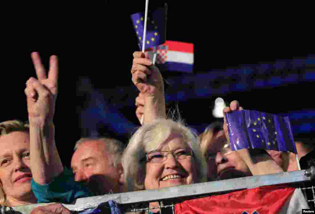 A woman makes victory sign as she holds the EU flag during the celebration of the accession of Croatia to the European Union in Zagreb, June 30, 2013.