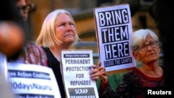  FILE - Refugee advocates hold placards and banners during a protest in central Sydney, Australia, Oct. 5, 2016, calling for the closure of the Australian detention centres in Nauru and Manus Island.