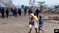 Une famille passe devant des policiers lors de manifestations à Kinshasa, RDC, le 19 septembre 2016.