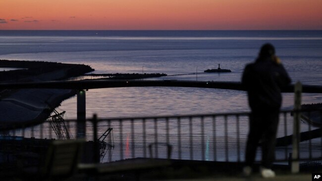 A local resident watches the coast from Hiyoriyama Park after a tsunami warning was issued for coastal towns in northeastern Japan in this photo taken by Kyodo on Jan. 16, 2022.