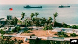 FILE - This photo released by the Military Information Agency in Taiwan shows two Taiwanese warships docking near the shore of Taiping Island, the largest of the disputed Spratly Island chain, with the Taiping military base in the foreground. 