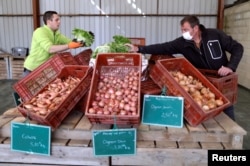 Vegetable grower Didier Lenoble, wearing a protective face mask, poses among boxes with vegetable put on sell during the outbreak of Coronavirus disease (COVID-19) in Perigny-sur-Yerres, France, March 31, 2020. (REUTERS/Charles Platiau)