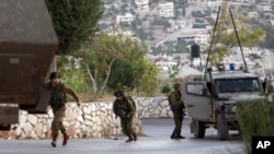 Israeli soldiers take positions during clashes with Palestinians as troops conduct a search for three missing Israeli teens in the West Bank village of Kabatyeh near Jenin, June 22, 2014.
