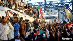 Sudanese demonstrators welcome a train carrying protesters from Atbara, the birthplace of an uprising that toppled Sudanese former President Omar al-Bashir, as they approach the military headquarters in Khartoum, April 23, 2019. 