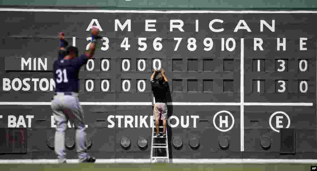 Boston Red Sox intern Tim Batesole changes the manual scoreboard during the sixth inning of an exhibition spring training baseball game against the Minnesota Twins in Fort Myers, Florida, March 18, 2015.