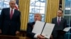 President Donald Trump shows off an executive order to withdraw the U.S. from the Trans-Pacific Partnership trade pact, Jan. 23, 2017, in the Oval Office of the White House in Washington.