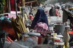 Seorang perempuan melihat barang-barang rumah tangga bekas yang dijual di sebuah pasar di lingkungan barat laut Khair Khana di Kabul, 12 September 2021. (AFP)