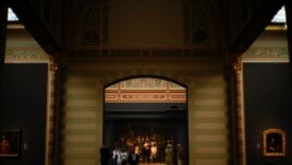 Museum director Taco Dibbits, rear center left in spotlight, explains how Rembrandt's biggest painting the Night Watch just got bigger with the help of artificial intelligence in Amsterdam, Netherlands, Wednesday, June 23, 2021. (AP Photo/Peter Dejong)