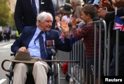 A boy greets a veteran in a wheelchair during the annual ANZAC (Australian and New Zealand Army Corps) Day march through central Sydney, Australia, April 25, 2017.