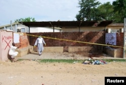 FILE - Security officers inspect the site where a female suicide bomber blew herself up at the campus of the Kano State Polytechnic, in Kano, northern Nigeria, July 30, 2014.