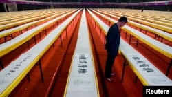 FILE - A visitor looks at a part of a Chinese calligraphy of Buddhist scriptures done by artist He Guojian on display at a stadium in Shenzhen, Guangdong province.