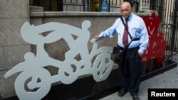Mexican artist Gilberto Aceves Navarro poses for a portrait with two of his bicycle sculptures in New York City, June 30, 2014.