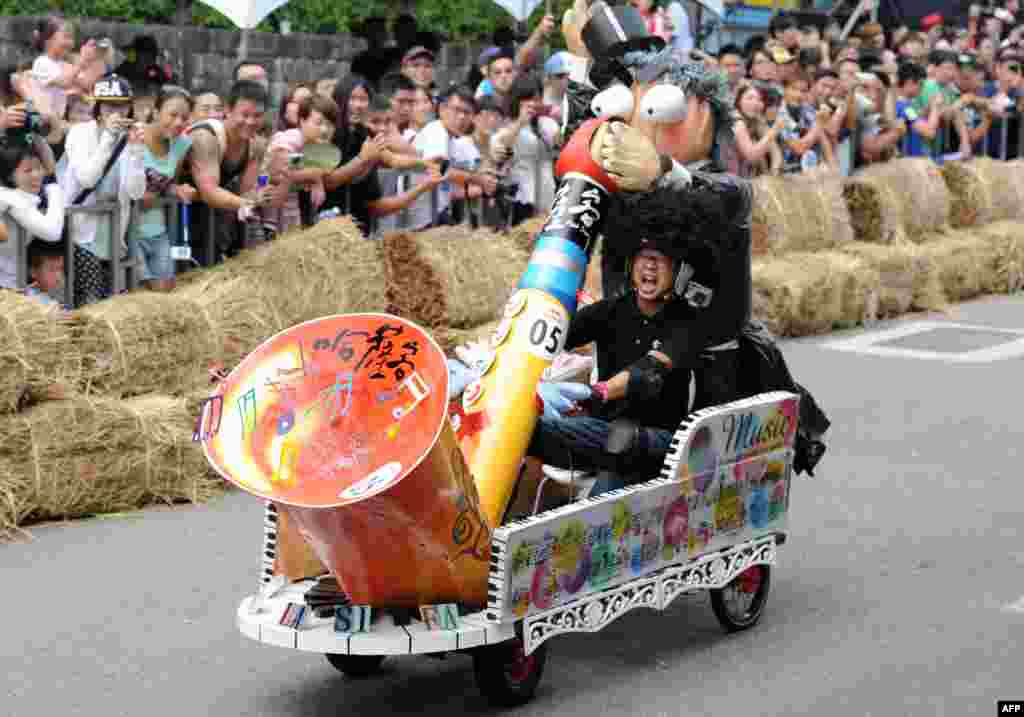 A man operates a saxphone-shaped vehicle during a race organized by the Red Bull Soapbox Race at the Taipei University of the Arts.  More then 50 vehicles take part in this 400-meter-long race. 