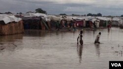 Residents of flooded protection site for people displaced by violence cross waist-high water as part of daily routine, Bentiu, South Sudan (G. Joselow/VOA).