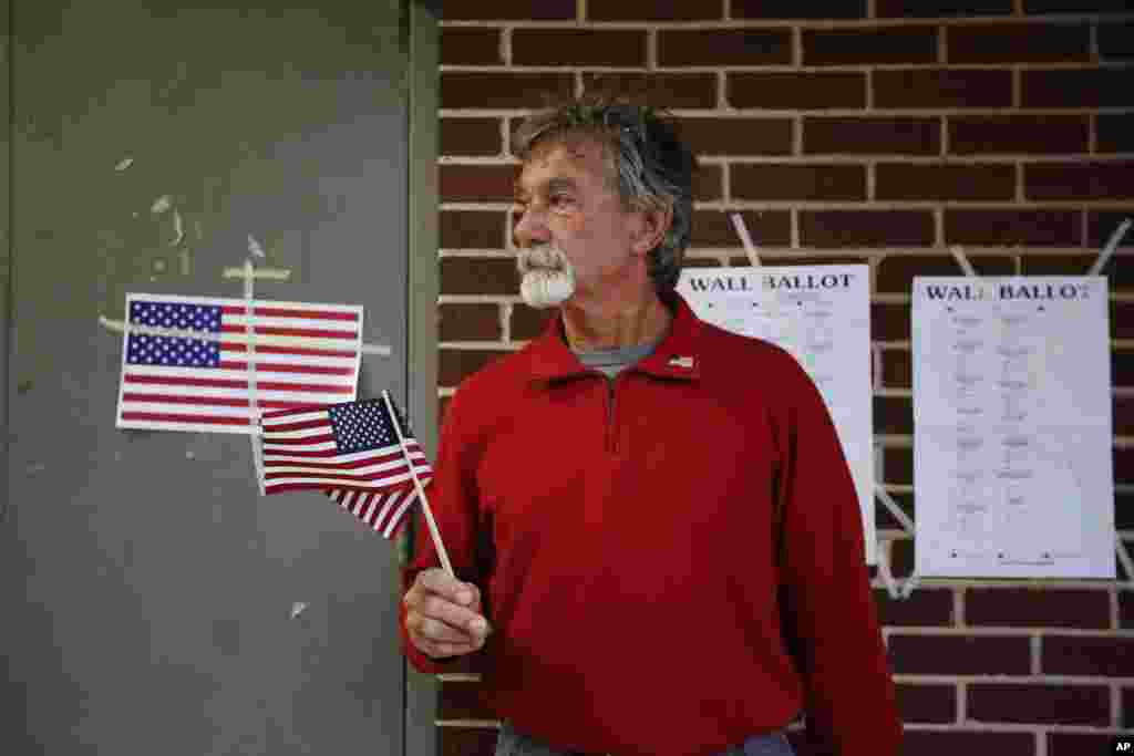 Republican and retired Roy Brook, 67, of Bessemer, Ala., stands outside the Muscoda Community Center holding American flags before being the first in line to vote, Nov. 8, 2016, in Bessemer, Ala. 