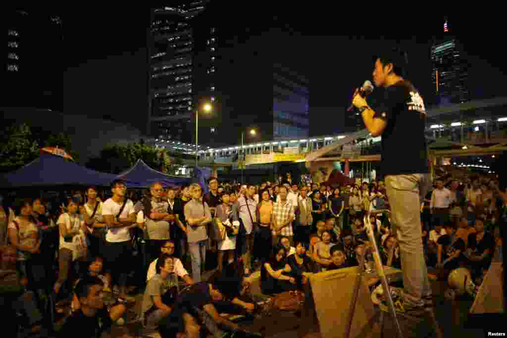 Pro-democracy demonstrators listen to a student&#39;s speech outside the government headquarters office in Hong Kong, Oct. 10, 2014. 