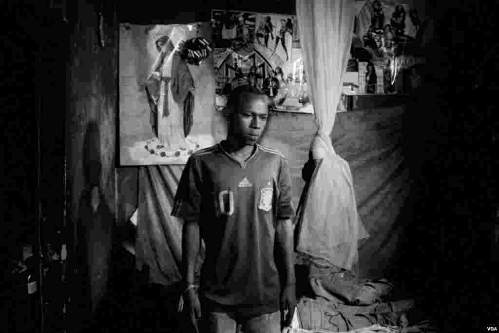 Kuitonda David, age 24, in his room at a billiards hall where he works. He takes turns, sleeping on the one bed in this room, with his work mate, Nzamwita Afrodis, who is HIV positive, Giporoso, Kigali, Rwanda, Nov. 27, 2013. (Hamada Elrasam for VOA)