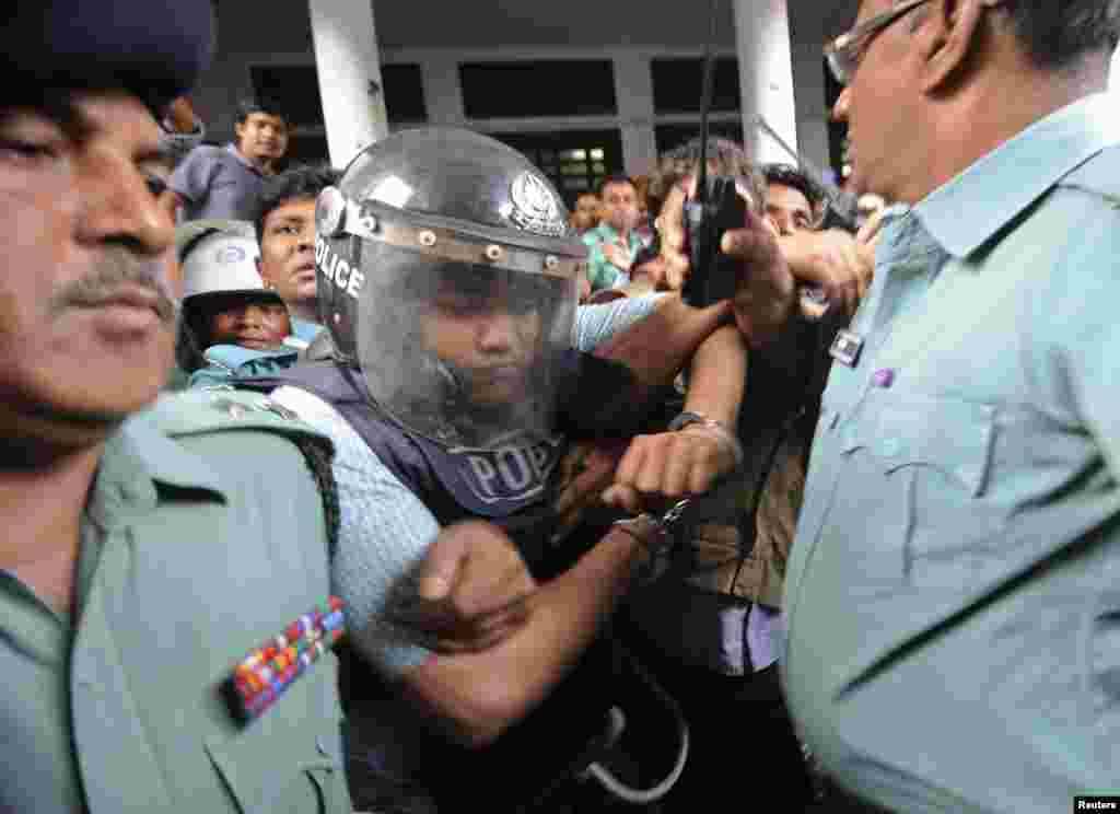Members of the police escort the owner of the collapsed building, Mohammed Sohel Rana, in a police helmet for protection after his hearing at the High Court in Dhaka, Bangladesh, April 30, 2013.