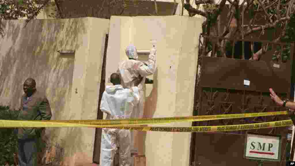 Les enquêteurs, centre, recueillent des débris après une explosion dans une discothèque qui a été attaquée par des hommes armés pendant que les forces armées assurent la sécurité à Bamako, au Mali, samedi 7 Mars 2015.