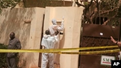 Les enquêteurs, centre, recueillent des preuves dans une discothèque qui a été attaquée par des hommes armés pendant que les forces armées assurent la sécurité à Bamako, au Mali, samedi 7 Mars, 2015.