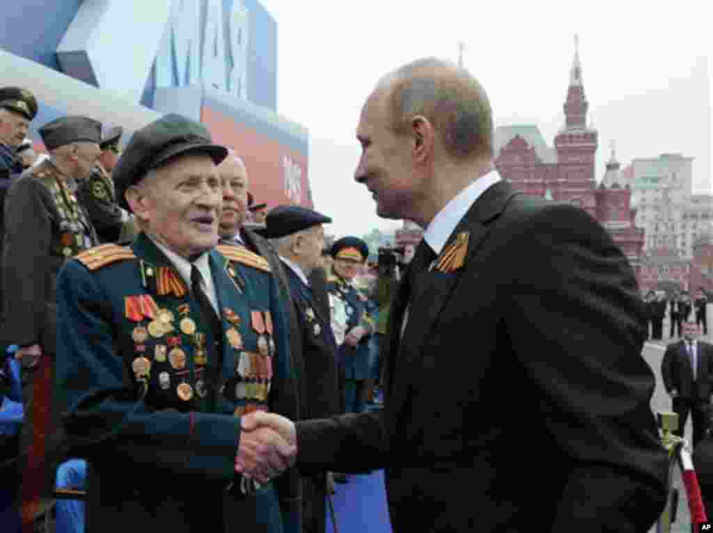 Russian President Vladimir Putin, right, shakes hands with a WWII veteran on the Red Square, during the Victory Day Parade, which commemorates the 1945 defeat of Nazi Germany in Moscow, Russia, Wednesday, May 9, 2012. Russian President Vladimir Putin has