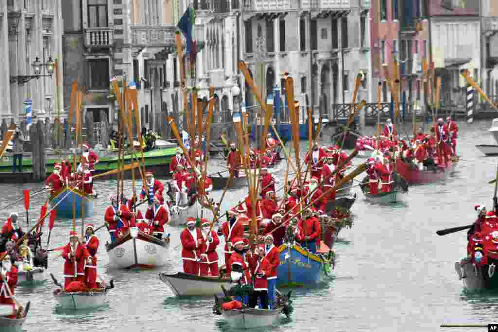 People wearing Santa Claus costumes sail along Venice&#39;s Grand Canal aboard traditional Venetians boats, Italy.