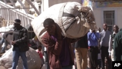 A vendor carries his goods after he was evicted from the streets by Zimbabwean police in Harare, Wednesday, July, 8, 2015. (AP Photo/Tsvangirayi Mukwazhi)