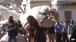 FILE: A vendor carries his goods after he was evicted from the streets by Zimbabwean police in Harare, Wednesday, July, 8, 2015.