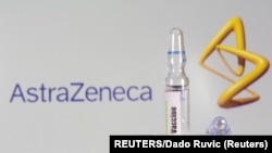 A test tube labeled with the vaccine is seen in front of AstraZeneca logo
