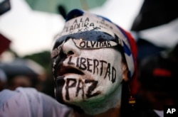 A woman with her face painted with Spanish words for; "Freedom, peace, don't forget," attends a vigil to honor the more than 90 people killed during three months of anti-government protests in Caracas, Venezuela, July 13, 2017.