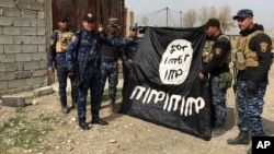Iraq's federal police forces celebrate as they hold a flag of the Islamic State group they captured after regaining control of Gawsaq neighborhood in the western side of Mosul, Iraq, Feb. 27. 2017.