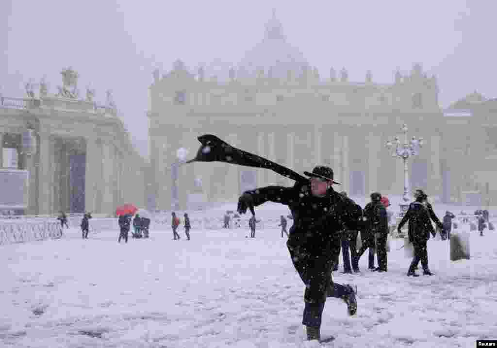 A young priest throws a snow ball during a heavy snowfall in Saint Peter&#39;s Square at the Vatican, Italy.