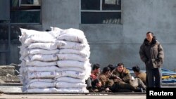 지난해 3월 북-중 국경 지역인 단둥에서 바라본 북한 신의주. 비료 더미가 쌓여있는 옆으로 북한 인부들이 앉아있다. (자료사진)