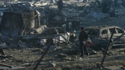 基辅的特雷维尔购物中心遭到俄军导弹袭击后，一名男子带着他的狗走过烧毁的车辆和废墟现场。(2022年3月21日)