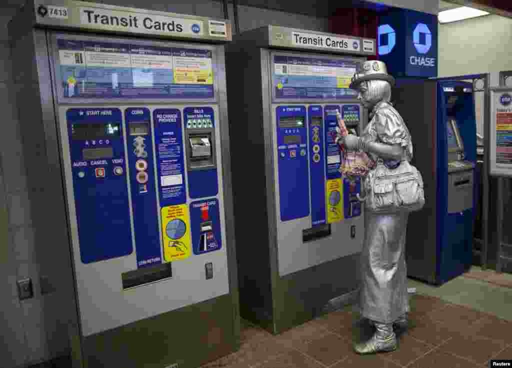 A protestor covered in silver paint purchases a rail ticket following an anti-NATO protest march. (Reuters)