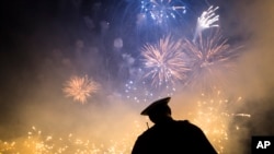 FILE - A Cincinnati Police officer stands beneath a Labor Day fireworks display as part of the city's Riverfest celebration on the Ohio River, Sept. 6, 2015.