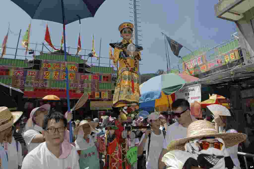 在香港长洲岛纪念包山节的游行活动中，一个穿着中国传统服饰的孩子被一根隐藏的金属杆支撑着，悬浮在空中。 