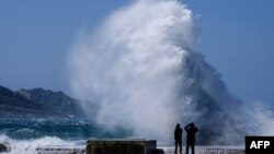 People watch heavy waves hiting the shore at the Plage du David beach in downtown Marseille, as storm Eleanor hits southern parts of France on May 5, 2019. 