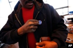 Albert Gates places a sticker on his chest after voting in the South Carolina Democratic primary at a polling place at Sanders Middle School in Columbia, S.C., Feb. 27, 2016.