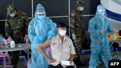 A man receives a dose of the Sinovac vaccine from China against the Covid-19 coronavirus at the Australian Centre for Education in Phnom Penh on May 1, 2021, as part of the government's campaign to halt the rising number of cases of the virus. (Photo by TANG CHHIN Sothy / AFP) 