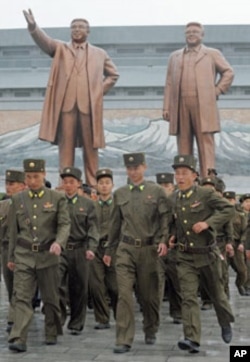 North Korean soldiers walk past bronze statues of North Korea founder Kim Il-sung (L) and late leader Kim Jong-il in Pyongyang, April 25, 2012.
