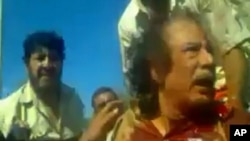 Image taken from amateur video posted on a social media website and obtained by Reuters, October 21, 2011, shows former Libyan leader Moammar Gadhafi, covered in blood, after his capture by NTC fighters in Sirte.