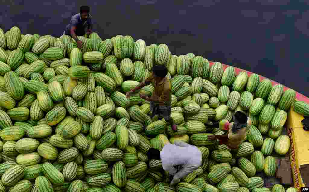 Workers unload watermelons from a boat in the river Burigangan, Bangladesh.