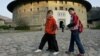 FILE - Schoolchildren pass by an old circular Tulou earth house, which are the traditional homes of China's minority Hakka people, in Yongding village, Fujian Province, December 15, 2005.