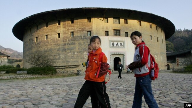 资料照:学童们走过福建省永定县洪坑村的客家土楼“振成楼”。(2005年12月15日) -