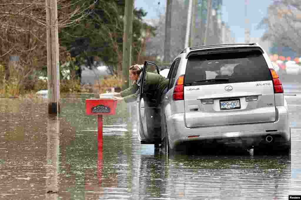 Renee Reeves delivers an apple crisp to a home in the evacuation area after rainstorms hit the western Canadian province of British Columbia, causing landslides and floods and shutting highways, in Abbottsford, British Columbia, Canada, Nov. 22, 2021.
