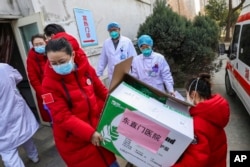 Doctors watch as donated medical supplies from Beijing are unloaded at a hospital in Wuhan in central China's Hubei Province, Thursday, Jan. 30, 2020. (Chinatopix via AP)