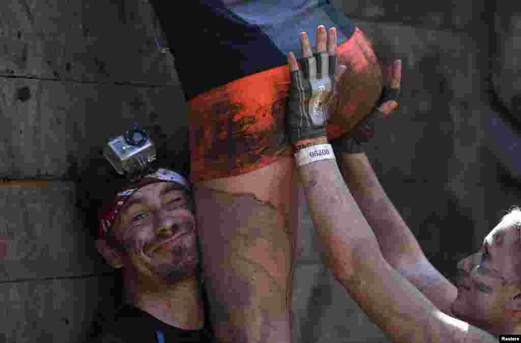 Participants climb over a wall at the &quot;Tough Mudder&quot; endurance event series in Arnsberg, Germany, Sept. 6, 2014.